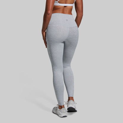 A person wearing high-waisted heather white leggings and running shoes, viewed from the back.