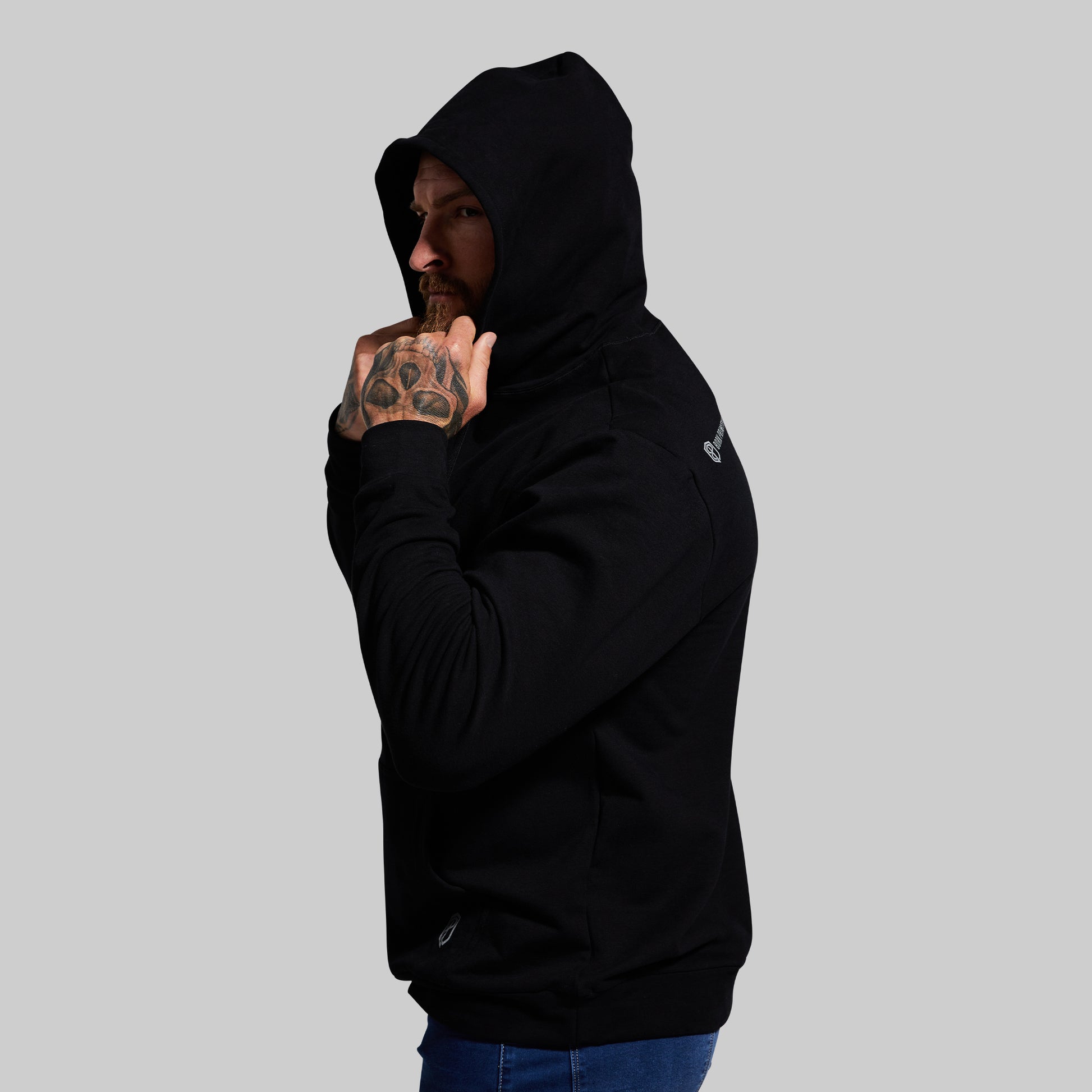 Person wearing a black hoodie with a logo on a gray background
