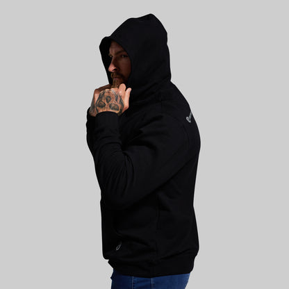 Person wearing a black hoodie with a logo on a gray background