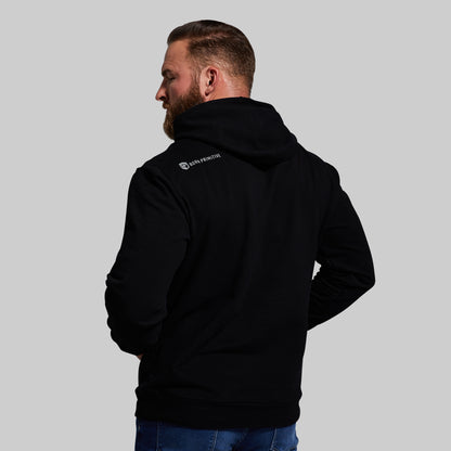 Man wearing a black hoodie with a brand logo on the back against a gray background