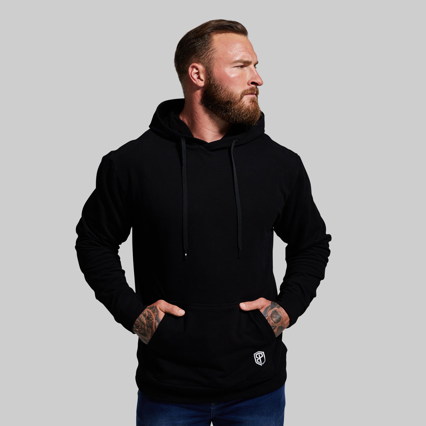 Man wearing a black hoodie with a small logo on a gray background