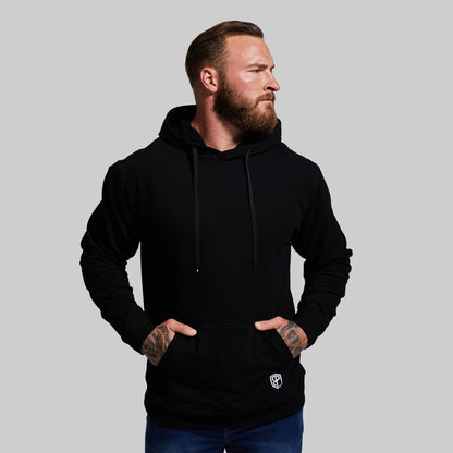 Man wearing a black hoodie with a small logo on a gray background