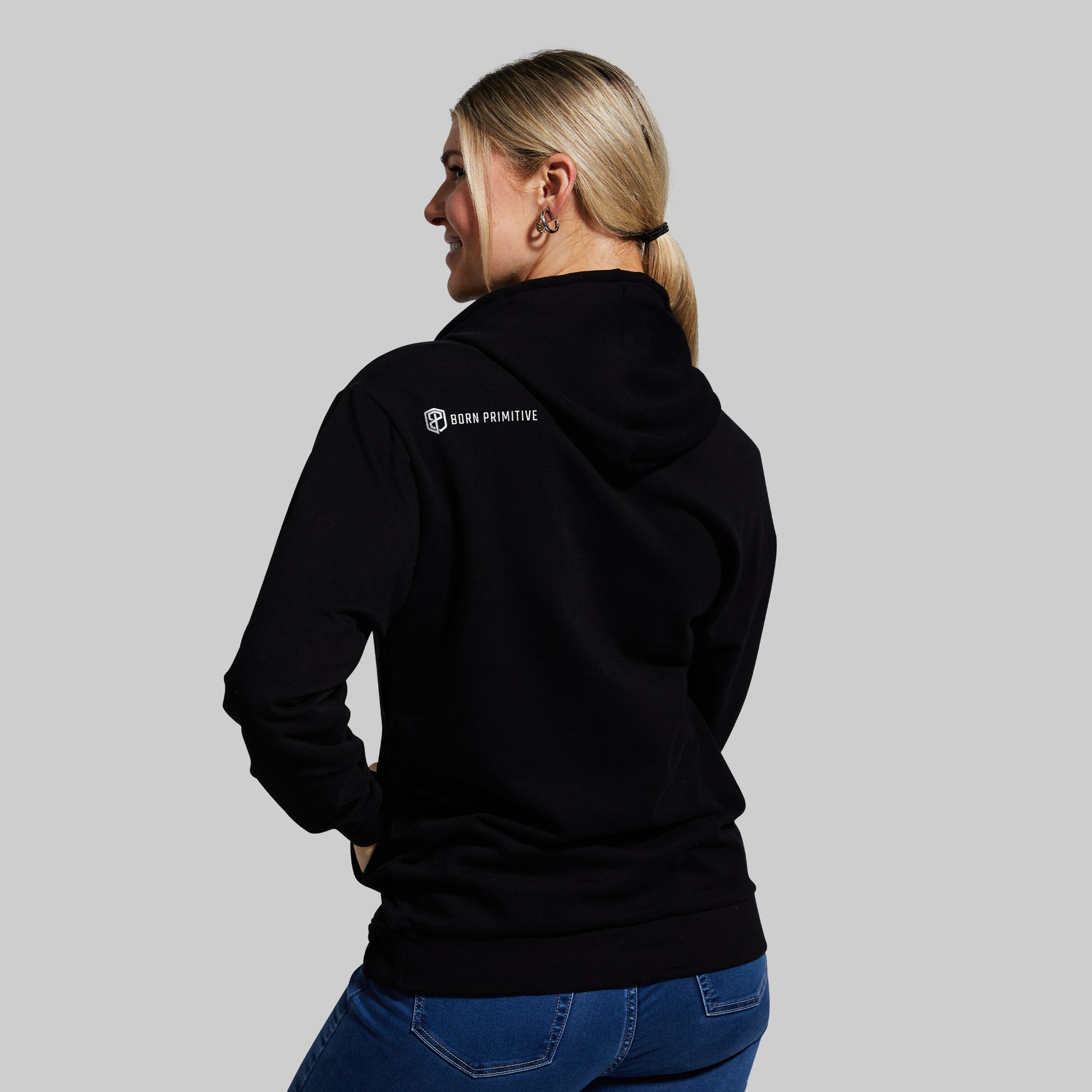 Person wearing a black hoodie with a logo on the back against a gray background