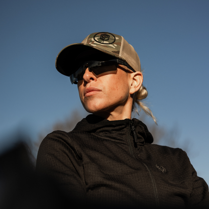 Person wearing a cap and sunglasses against a clear blue sky