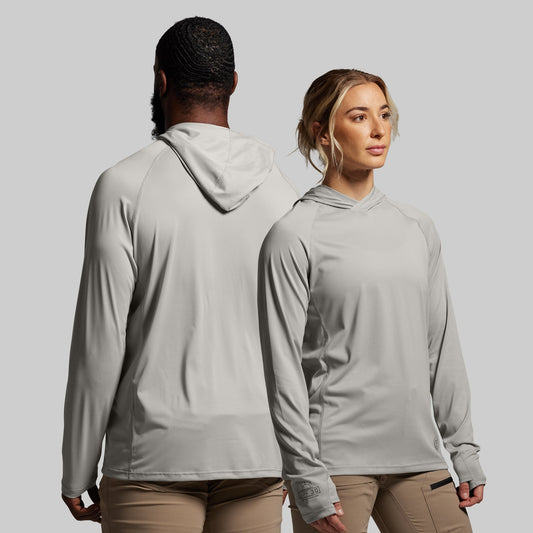 Two people wearing gray hoodies and beige pants against a plain background