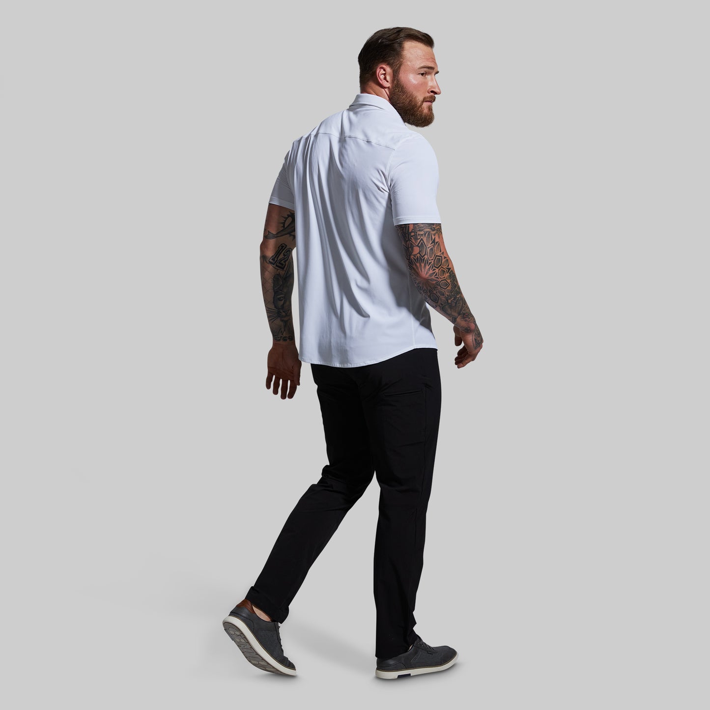 Man wearing a white shirt and black pants on a gray background