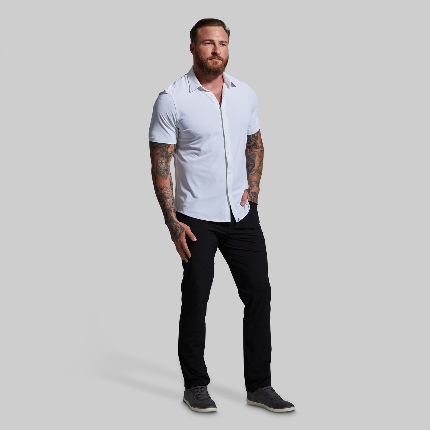 Man wearing a white shirt and black pants on a gray background