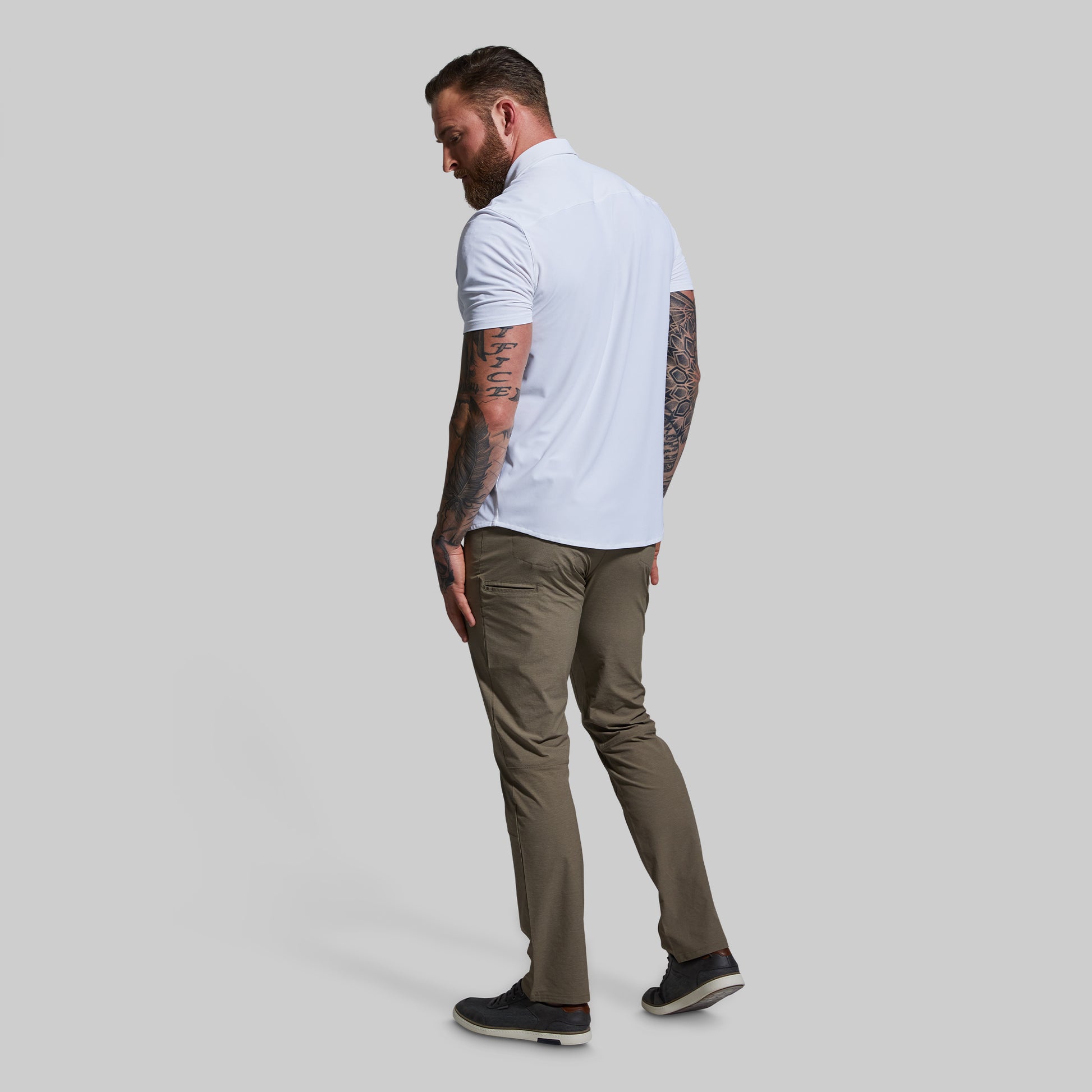Man wearing a white shirt and khaki pants on a plain background