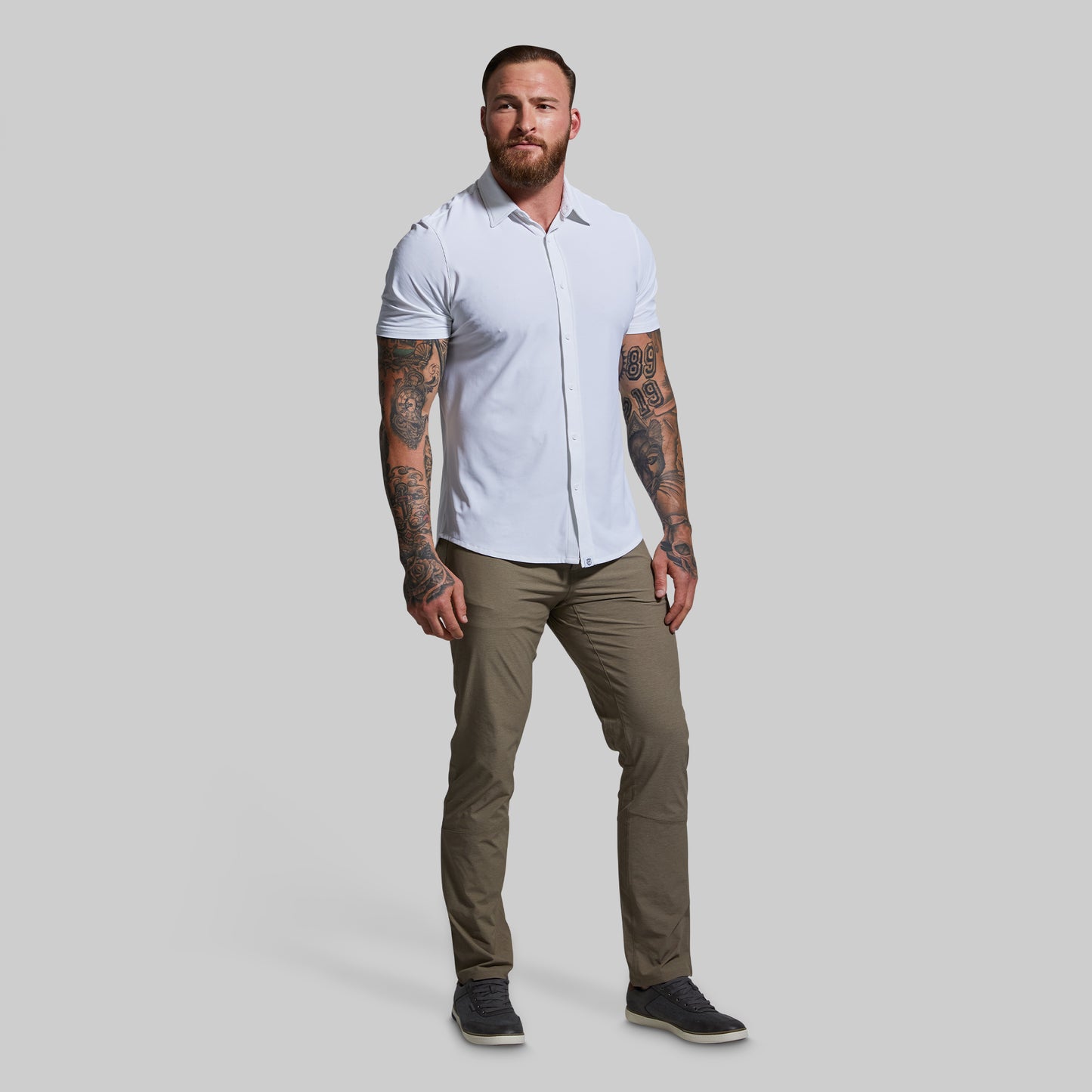 Man wearing a white shirt and beige pants on a gray background