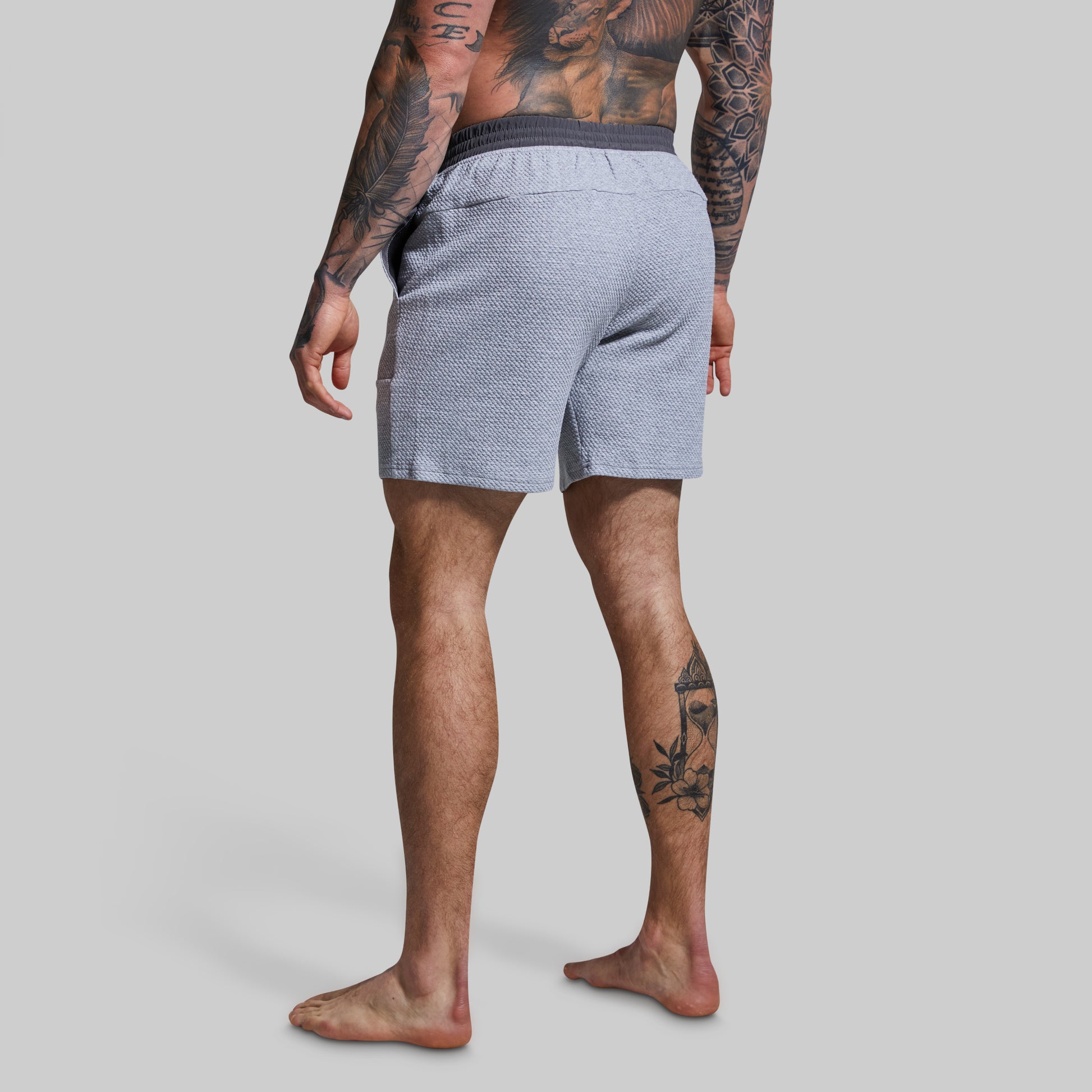 Person wearing gray textured shorts on a plain background