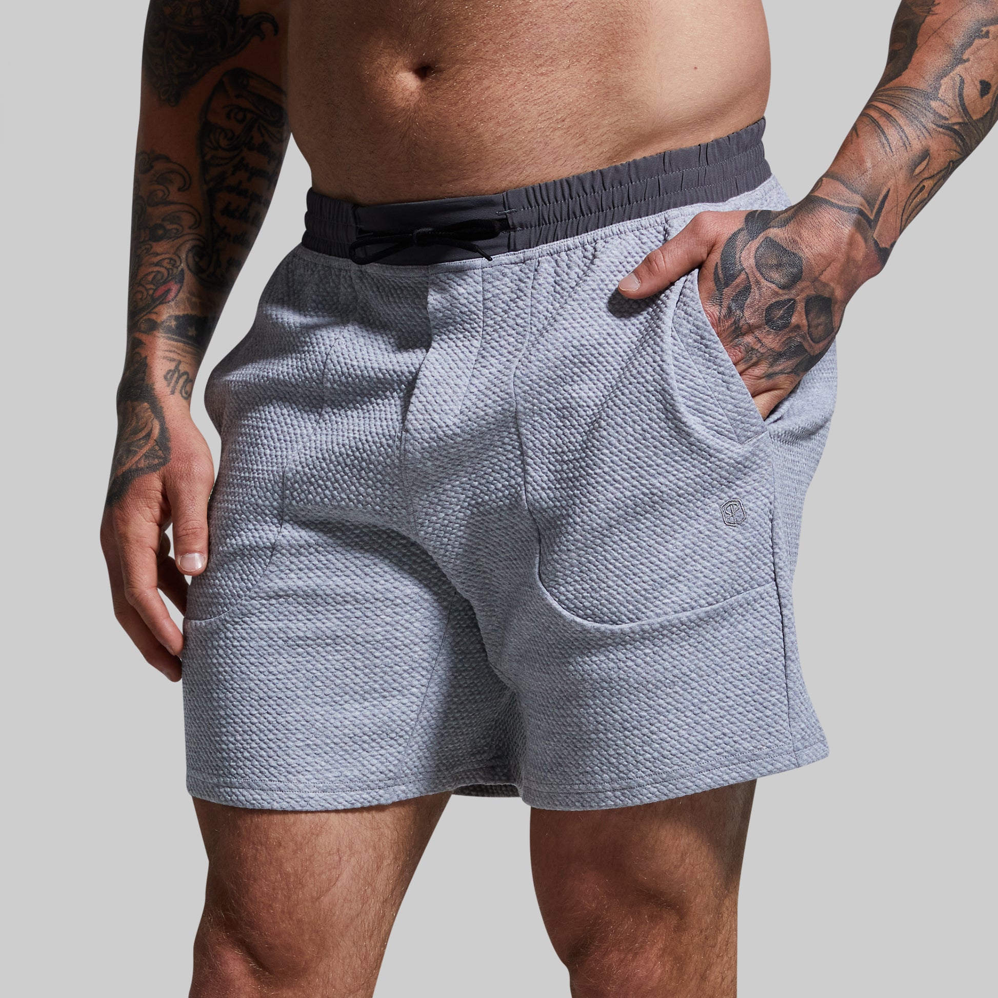 Person wearing light gray textured shorts on a plain background