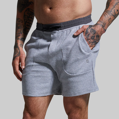 Person wearing light gray textured shorts on a plain background