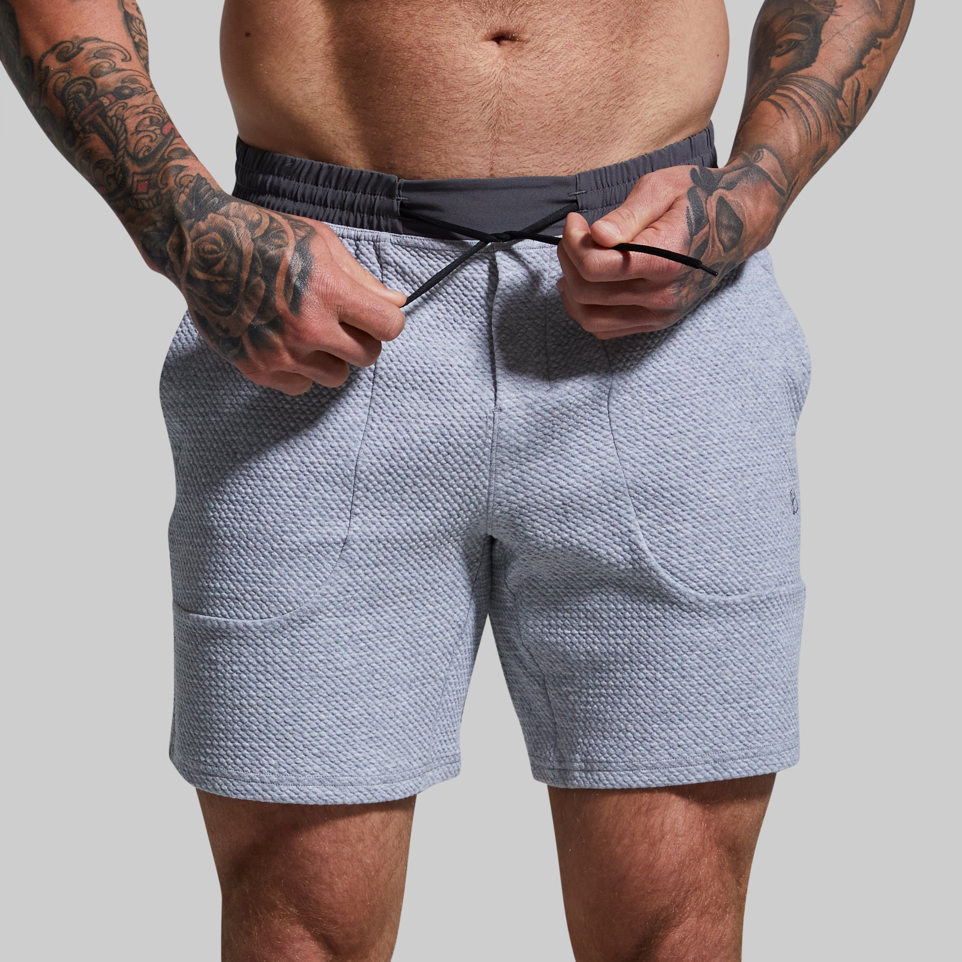 Person wearing light gray textured shorts with a gray background