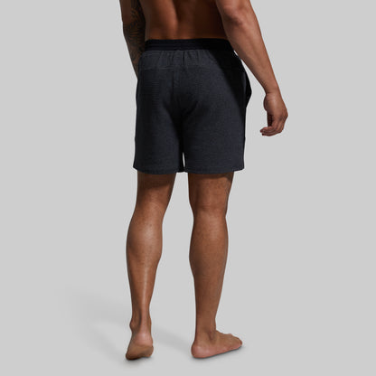 Person wearing dark gray shorts on a plain background