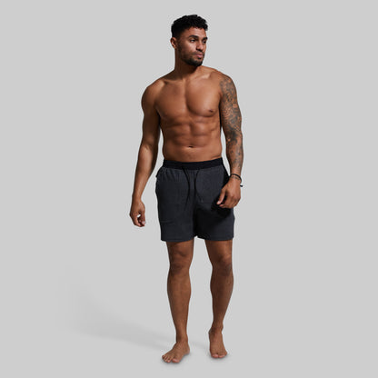 Man wearing dark gray lounge shorts on a gray background
