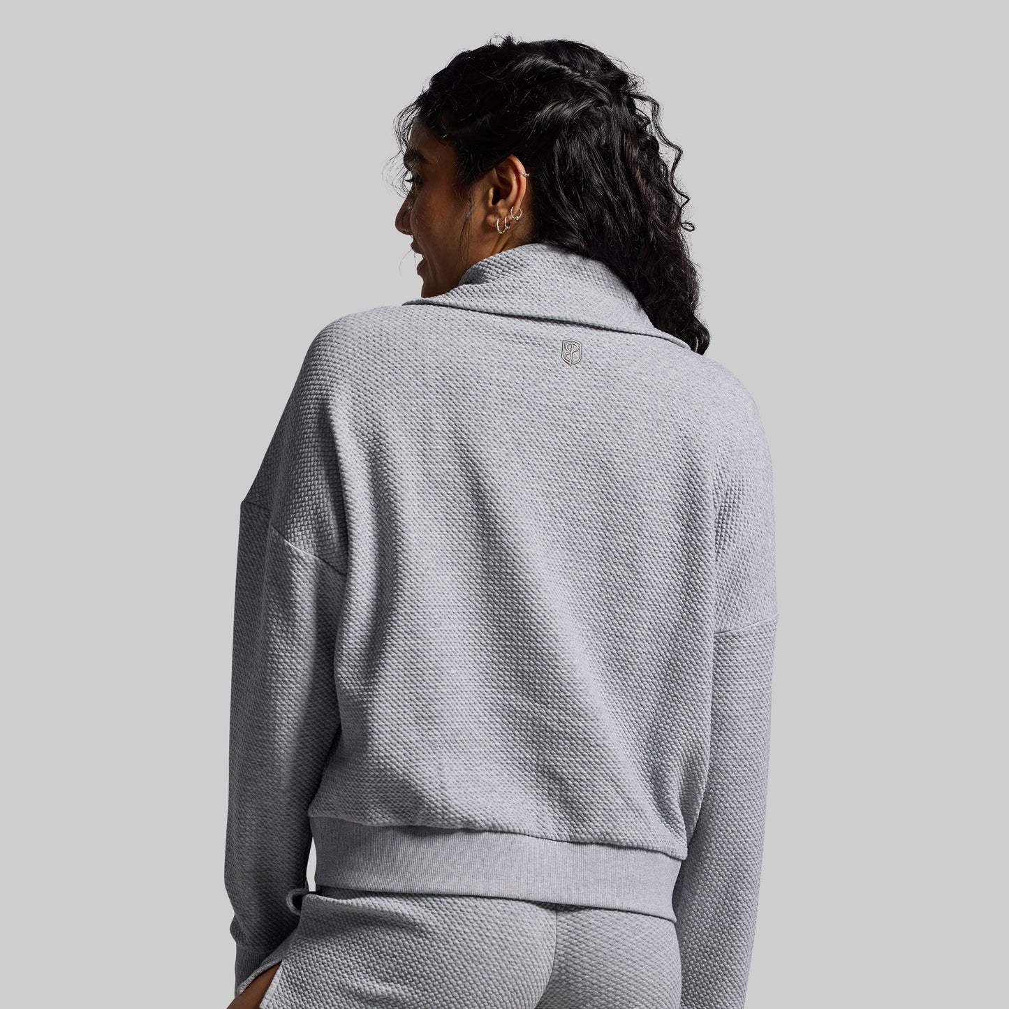 Person wearing a gray textured sweater against a plain background