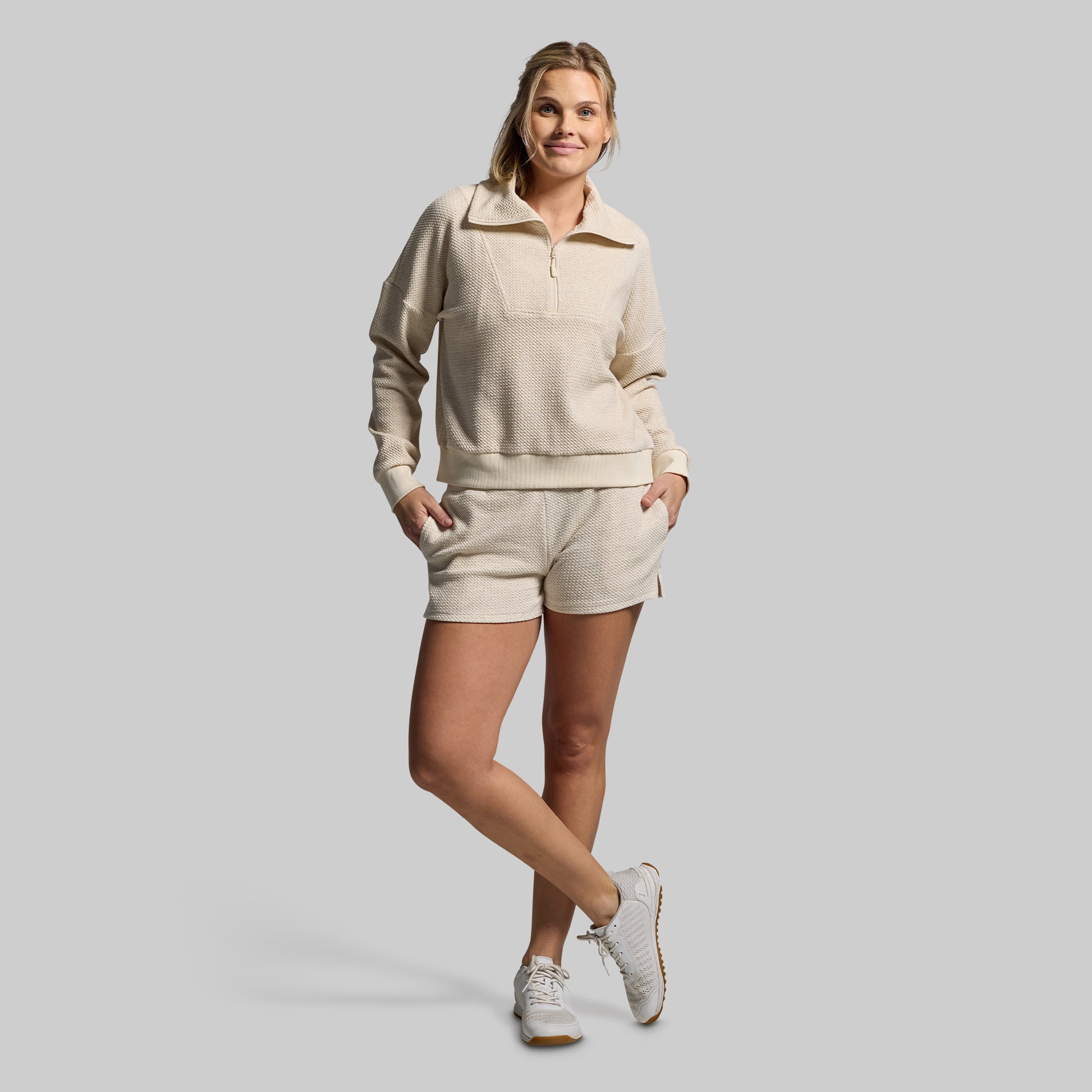 Woman wearing a beige tracksuit on a gray background