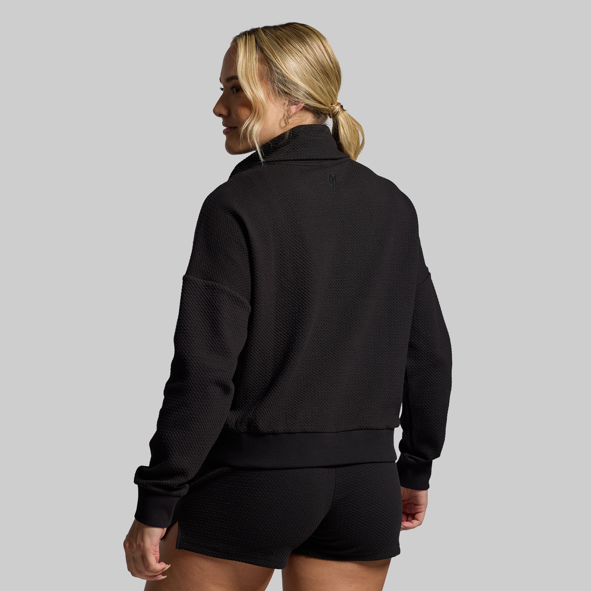 Person wearing a black pullover with a gray background
