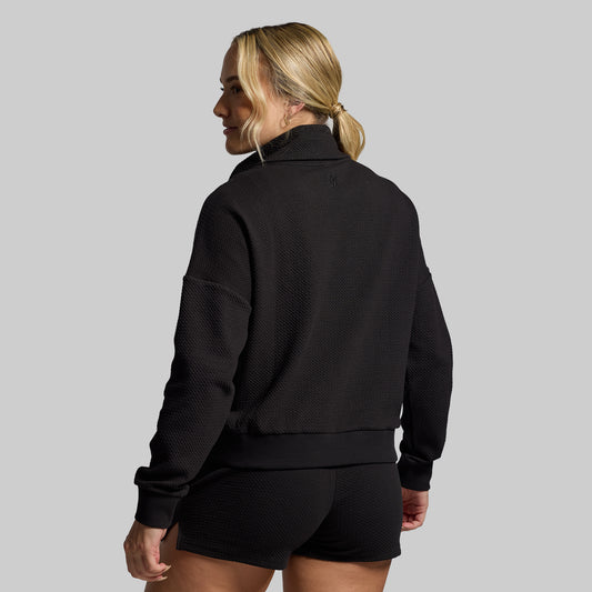 Person wearing a black pullover with a gray background