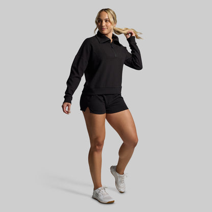 Woman wearing a black outfit with white sneakers on a gray background