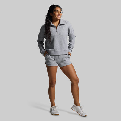 Woman wearing a gray sweatshirt and shorts set on a light gray background