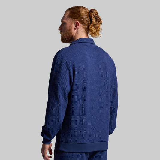 Man wearing a blue pullover viewed from back against a gray background
