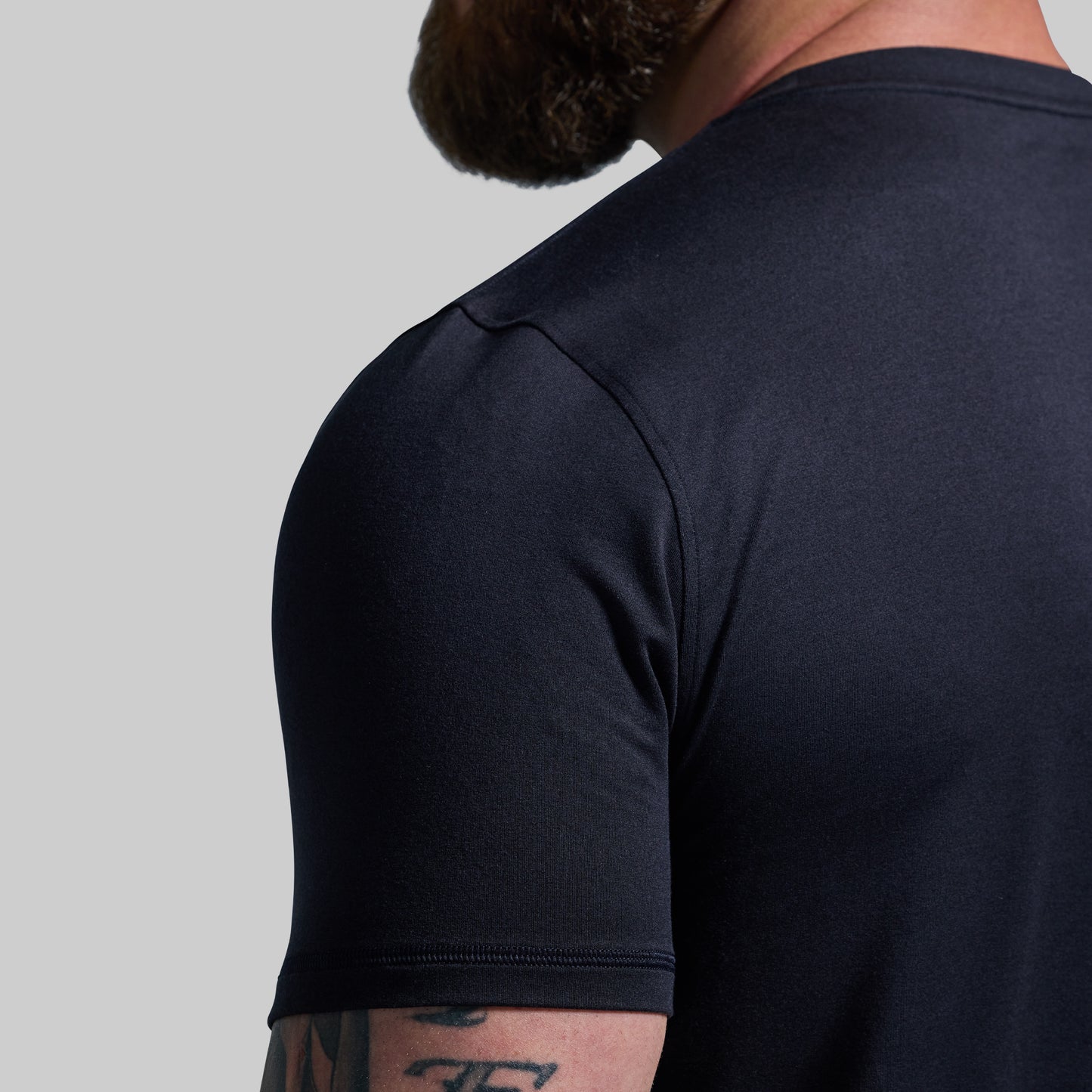 Person wearing a black t-shirt on a gray background