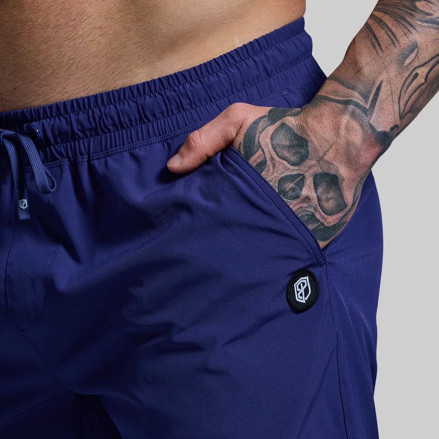 Person wearing blue shorts with a brand logo on a gray background