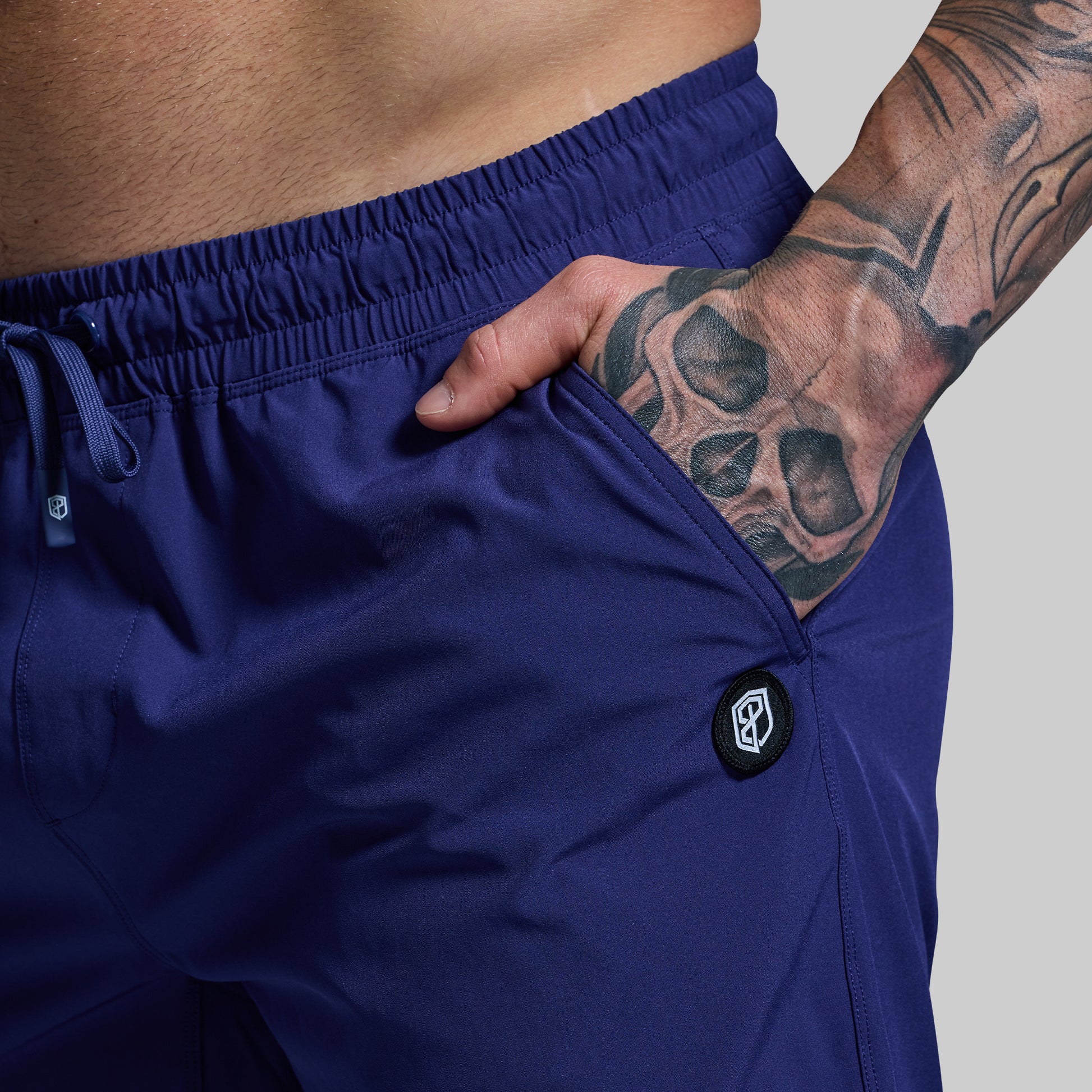 Person wearing blue shorts with a brand logo on a gray background