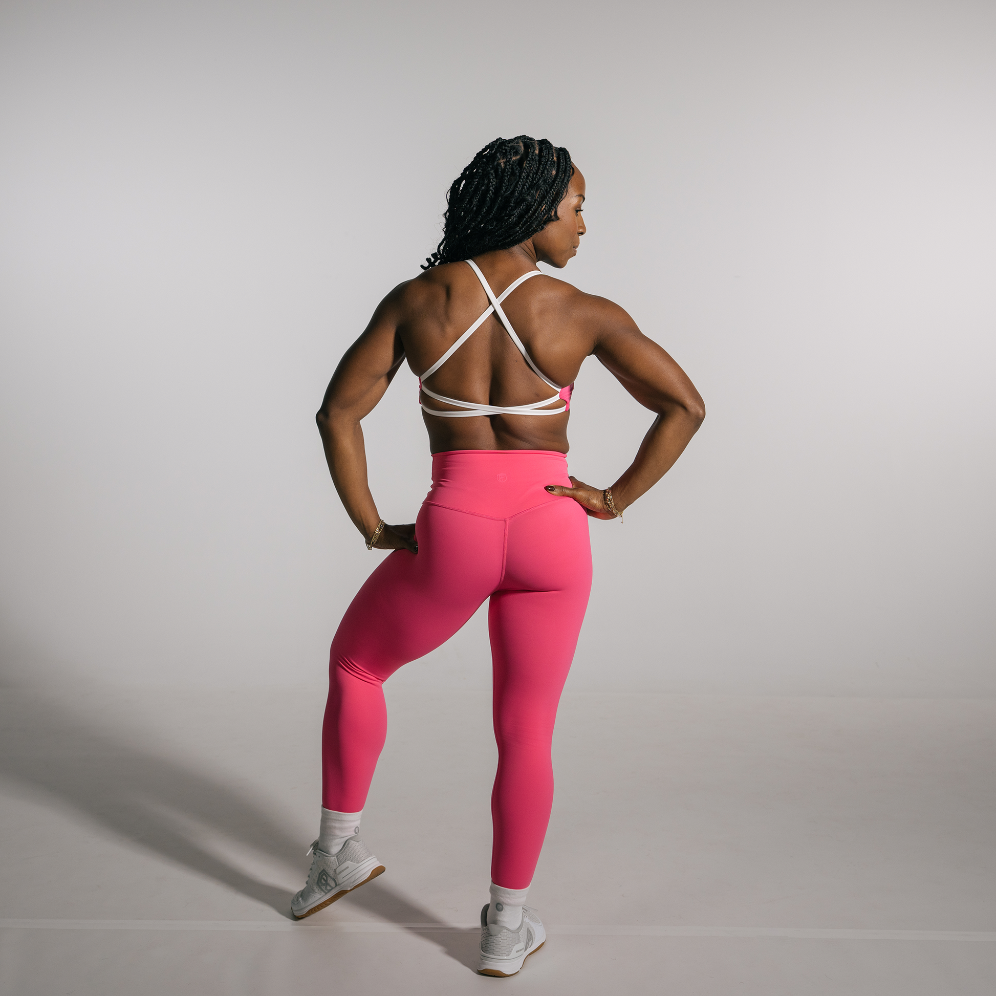 Person wearing pink leggings and a white sports bra against a plain background