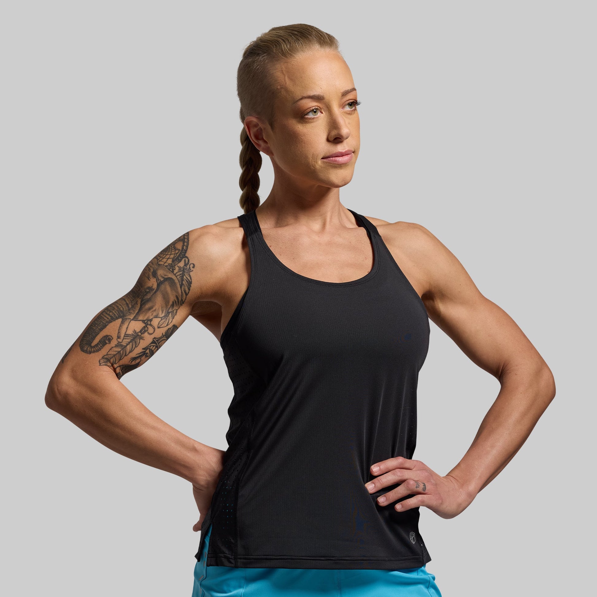 Woman wearing a black tank top against a gray background