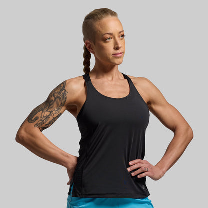 Woman wearing a black tank top against a gray background