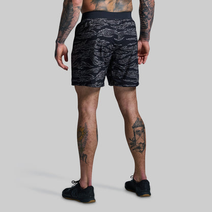 Person wearing black camouflage patterned shorts on a gray background