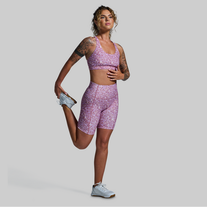 Woman in a purple athletic outfit posing against a gray background