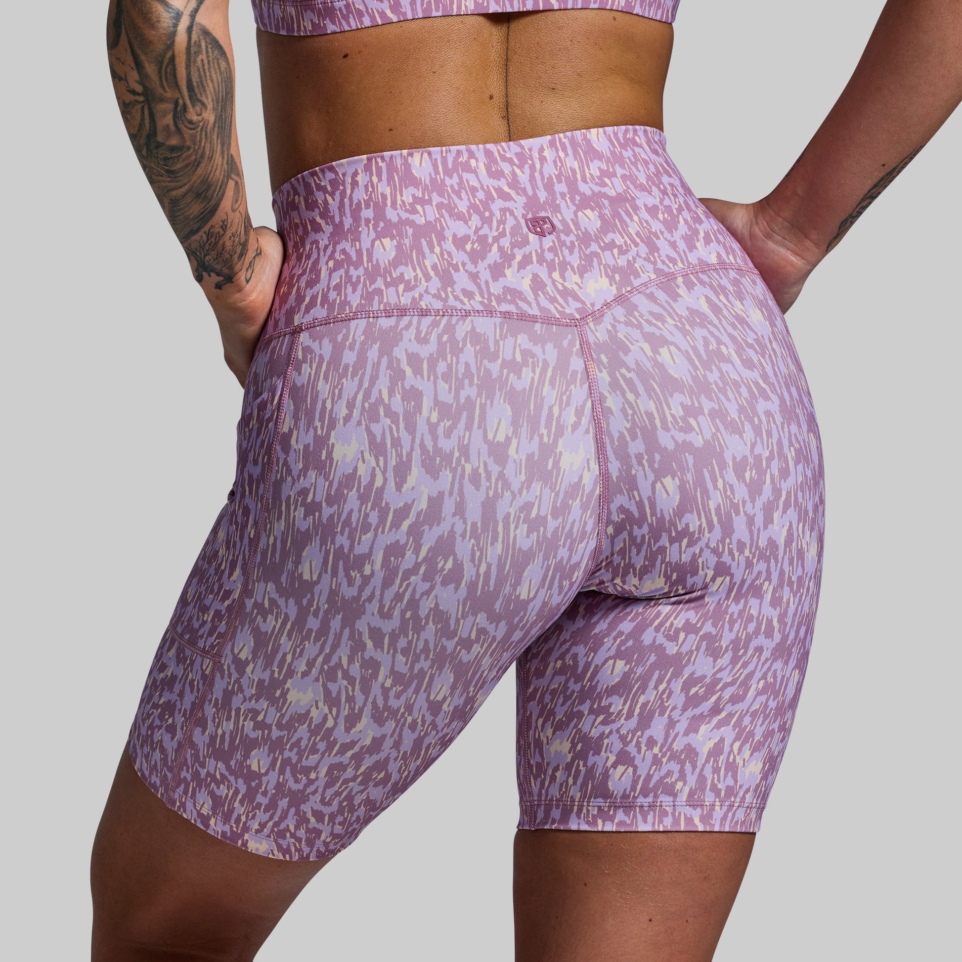 Purple patterned shorts worn by a person on a gray background