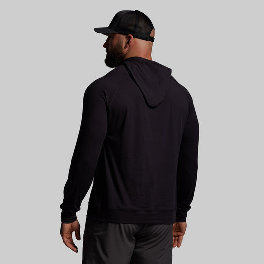 Man wearing a black hoodie and cap from behind on a gray background