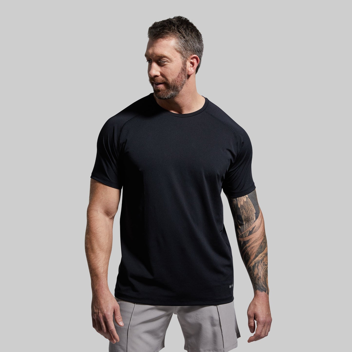 A man wearing a black short-sleeved crew neck t-shirt.