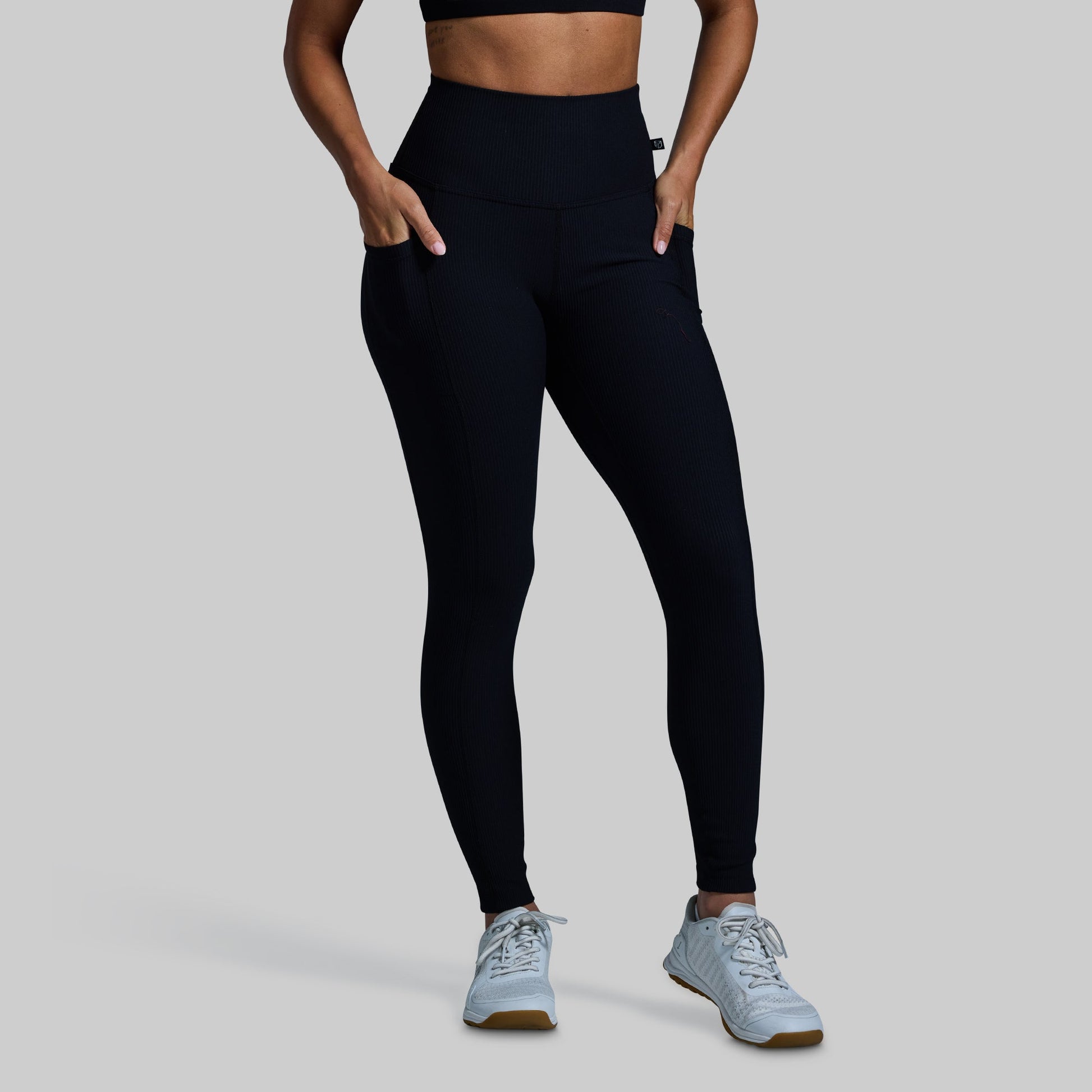 Person wearing black leggings and light blue sneakers on a gray background