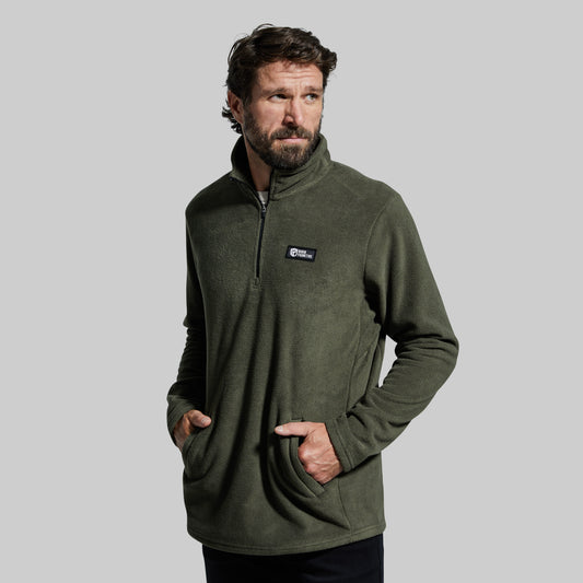A man wearing a green Cabin Fleece with a quarter-zip front, long sleeves, and two front zippered pockets.