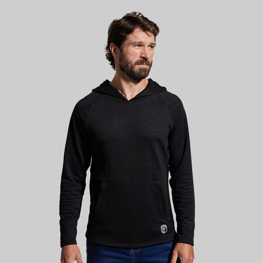 A male model wearing a black hooded Grid Fleece hoodie with a front pouch pocket, standing against a plain background.