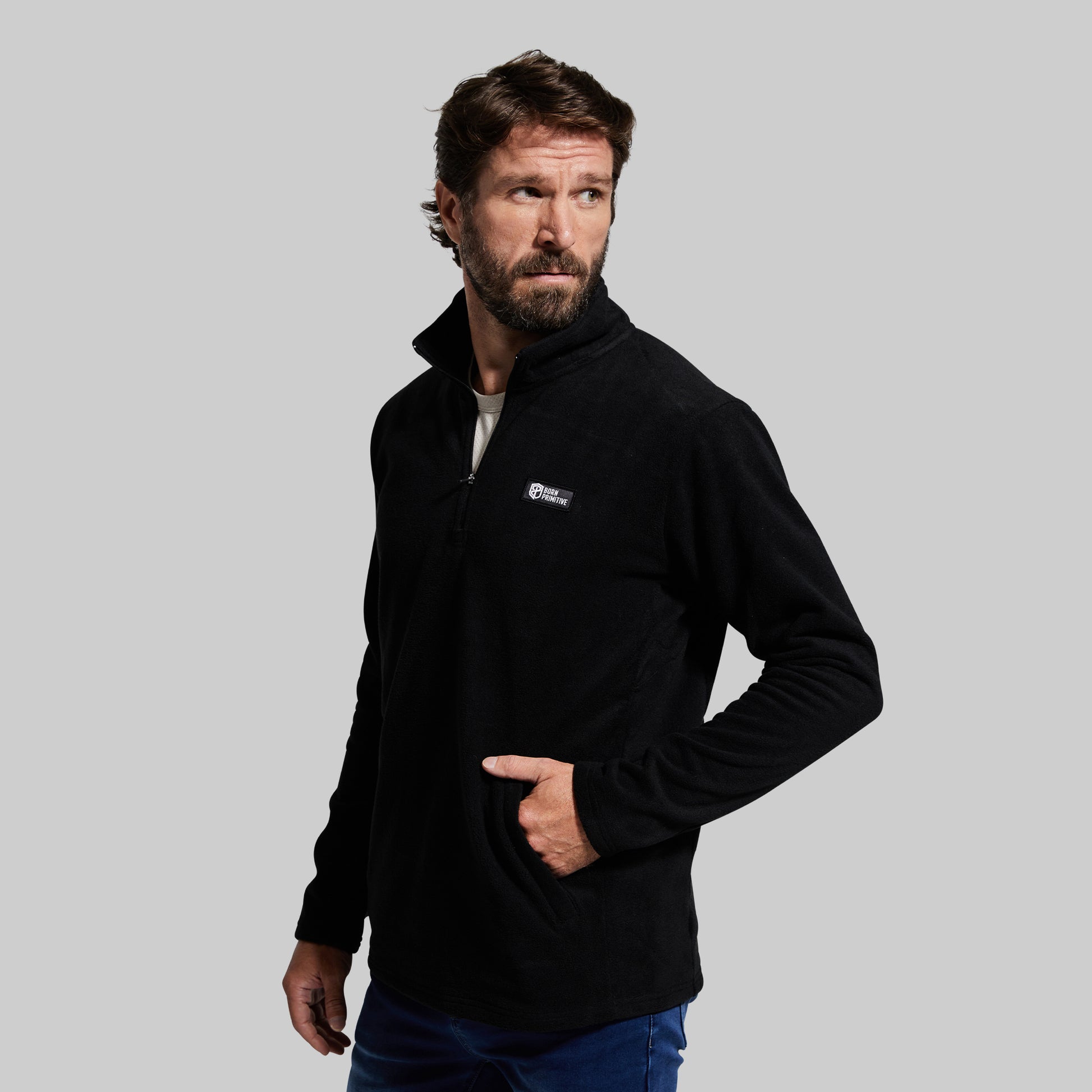 A person wearing a black long-sleeve fleece jacket with two front zippered pockets, standing against a plain background.