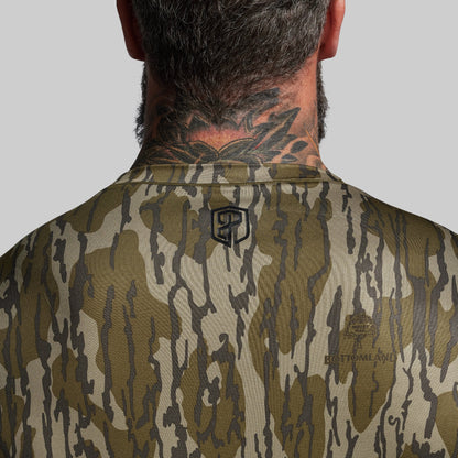 Camouflage shirt with a brand logo on the back, worn by a person.
