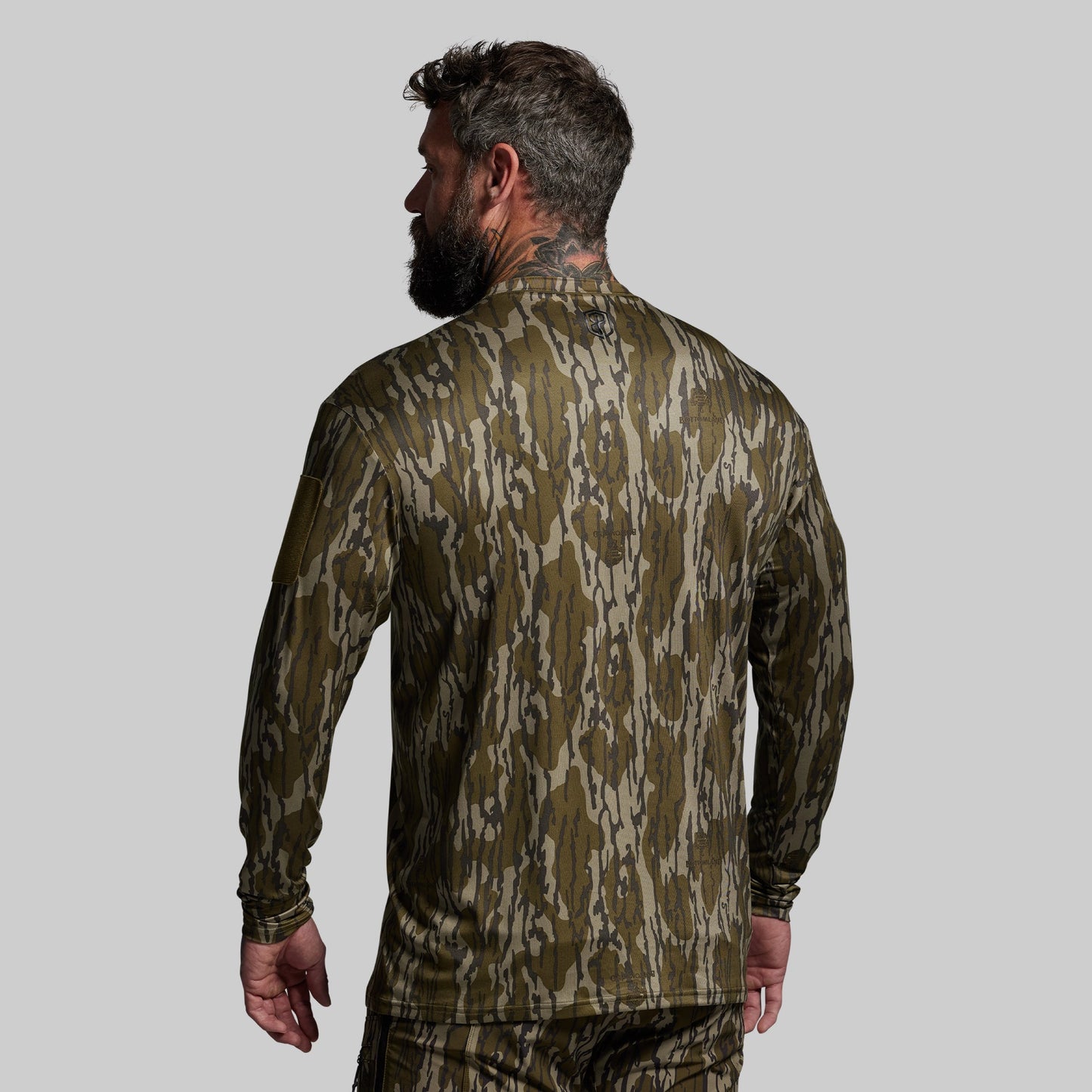 Man wearing a camouflage long-sleeve shirt on a gray background
