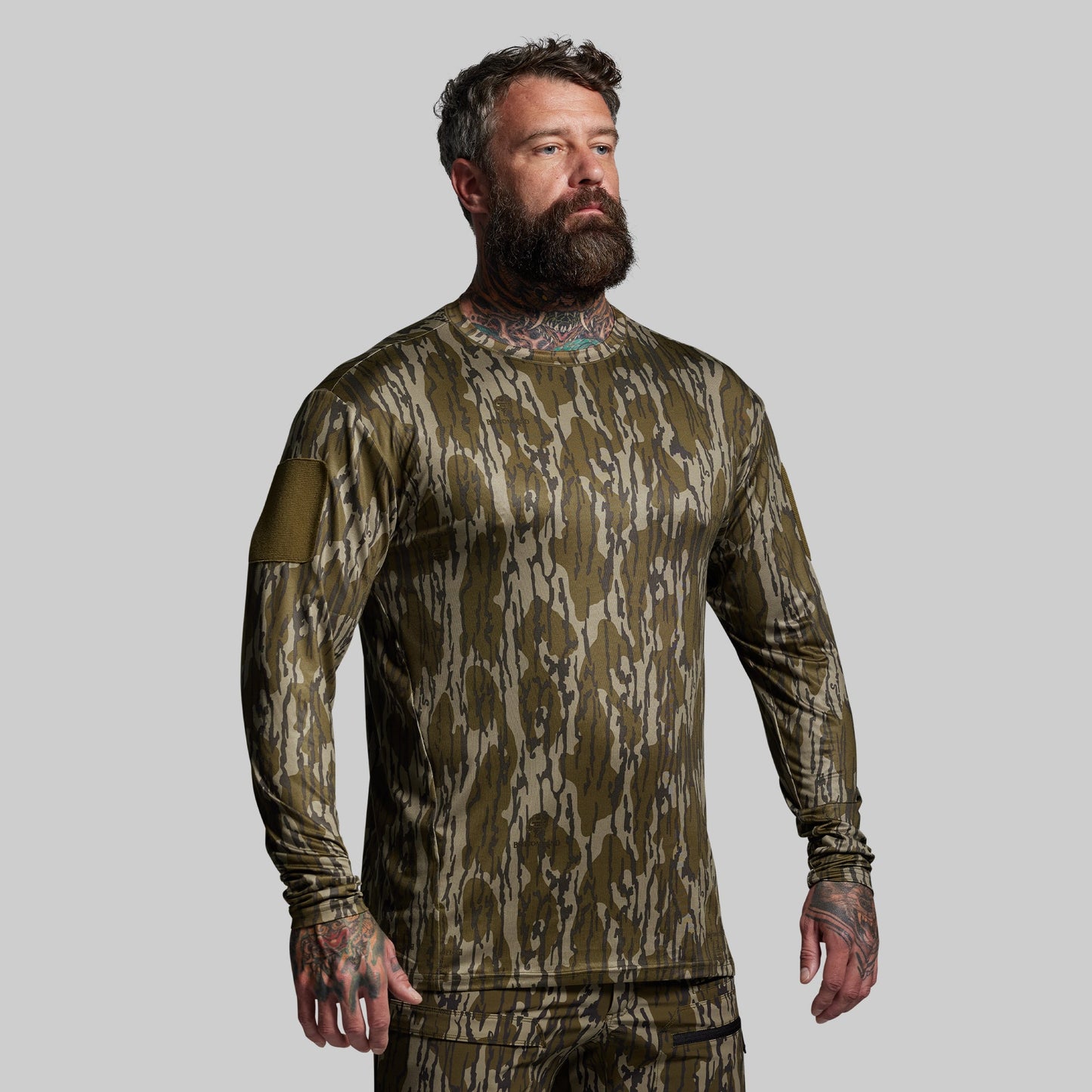 Man wearing a camouflage long-sleeve shirt on a gray background