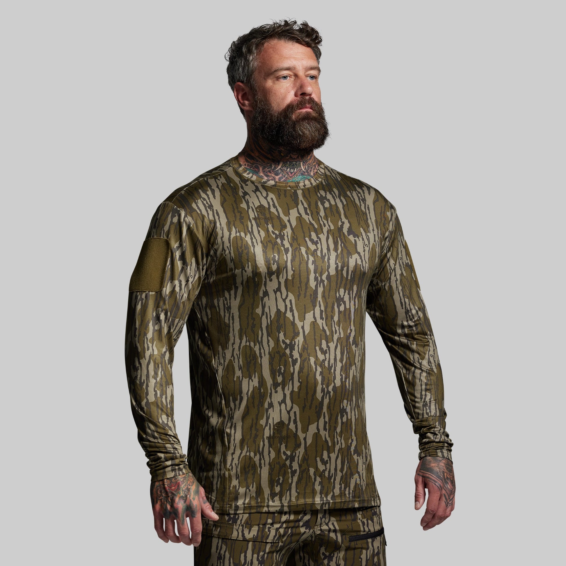 Man wearing a camouflage long-sleeve shirt on a gray background