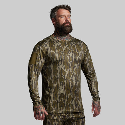 Man wearing a camouflage long-sleeve shirt on a gray background