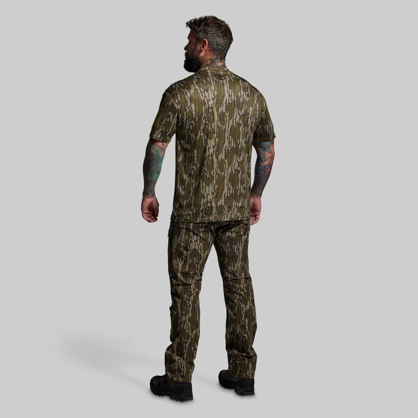 Man wearing camouflage hunting outfit on a gray background