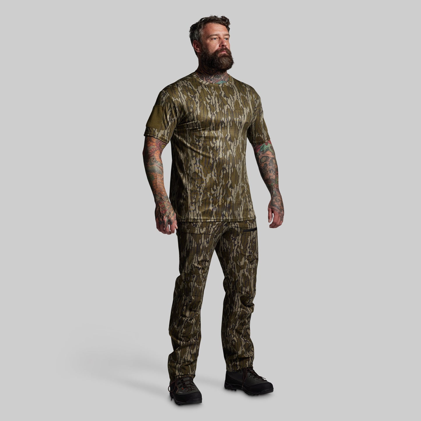 Man wearing camouflage hunting attire on a gray background