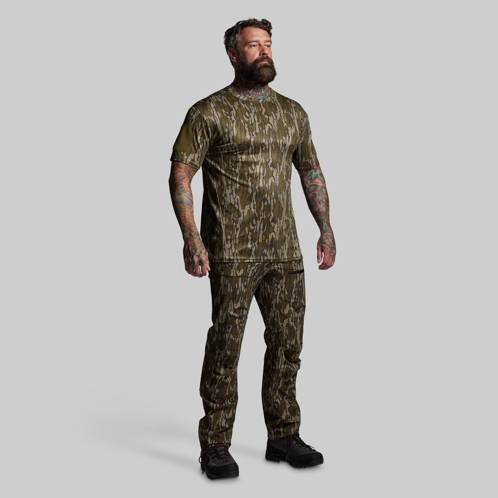 Man wearing camouflage hunting attire on a gray background