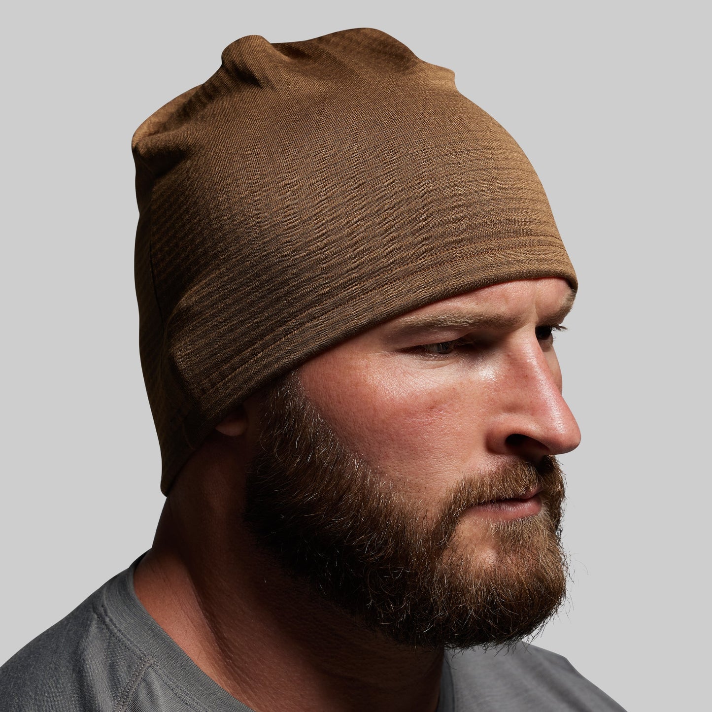 Man wearing a brown beanie against a gray background